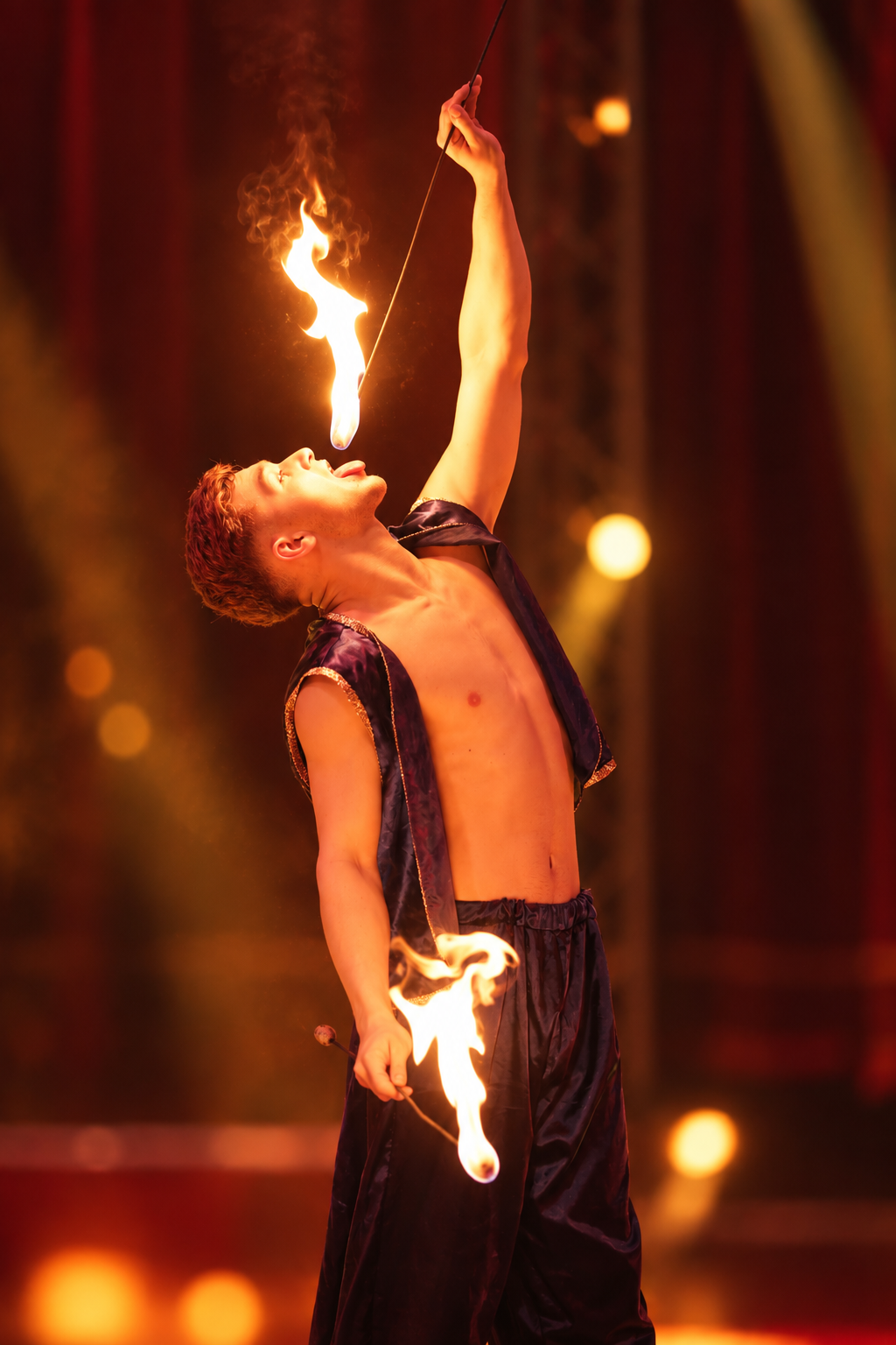 Feuerschlucker führt seine Show mit brennenden Fackeln in der Manege vor