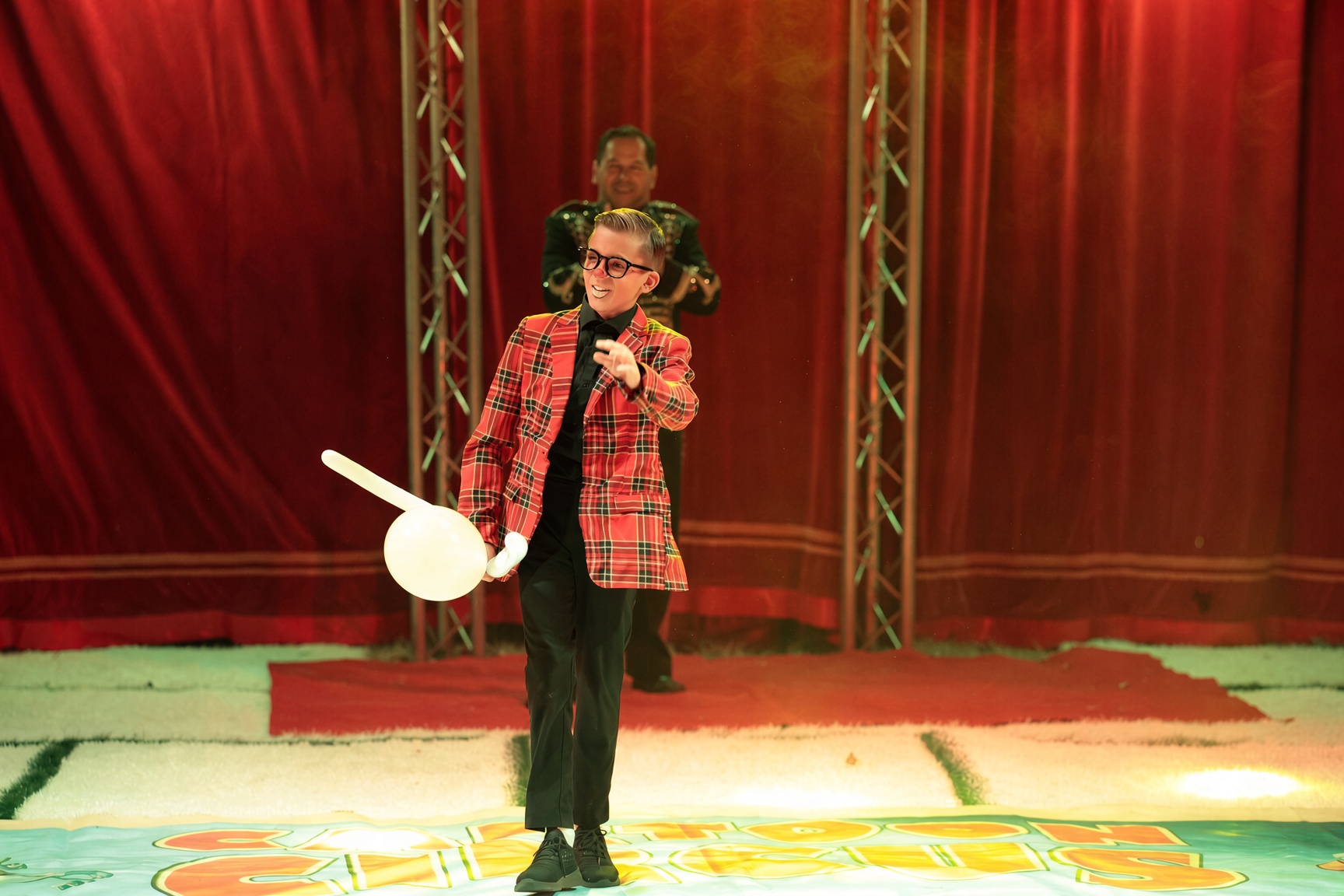 Clown in kariertem Jackett steht in der Manege